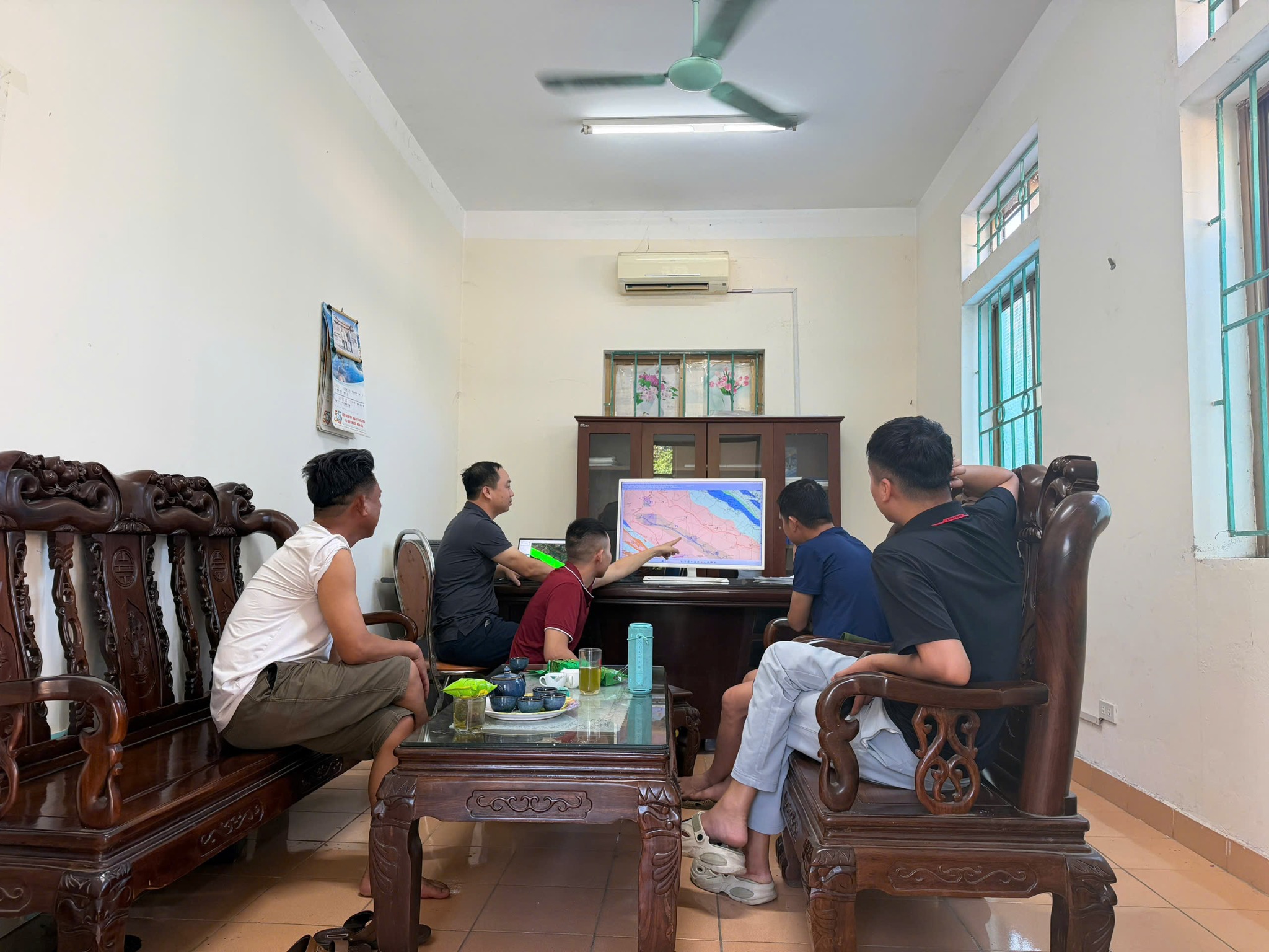 Các thành viên trao đổi trước màn hình bản đồ, một người chỉ vị trí để khoanh vùng khảo sát nguồn nước